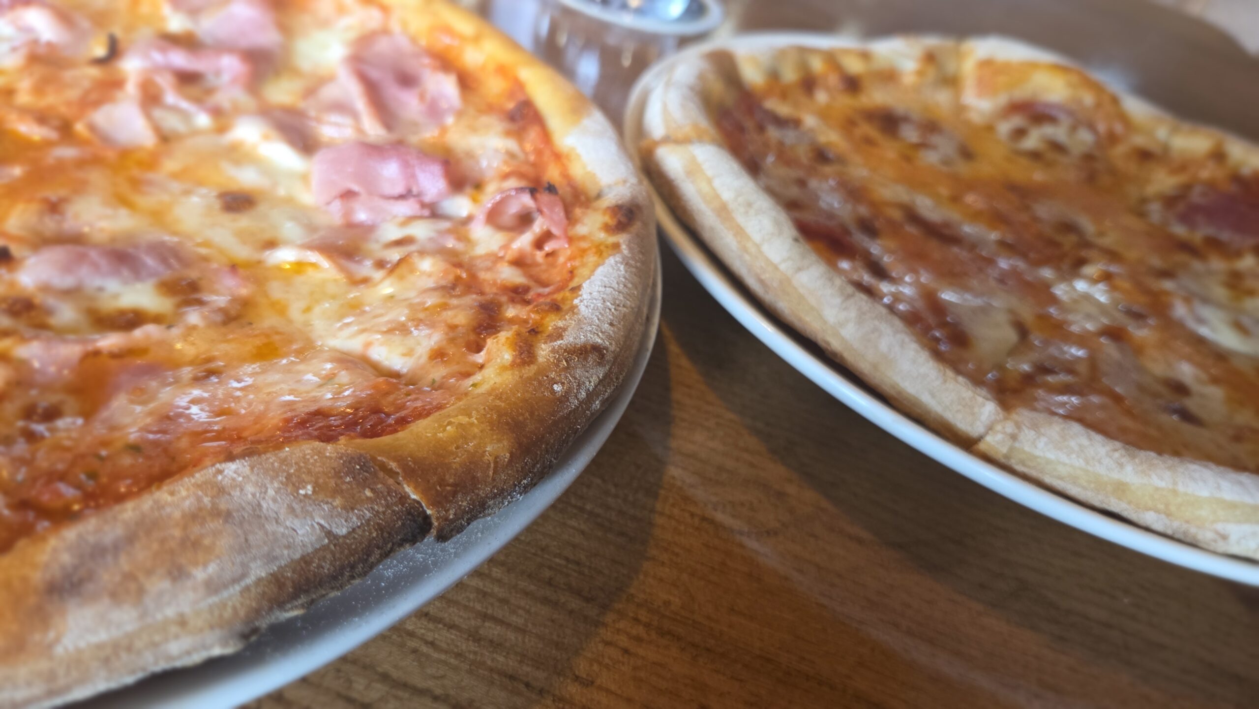 Zwei frisch gebackene Pizzen mit knusprigem Rand im Restaurant Perlacher Bachgarten München Perlach“